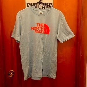 The North Face, shirt color: blue w/ orange lettering. Shirt size: medium